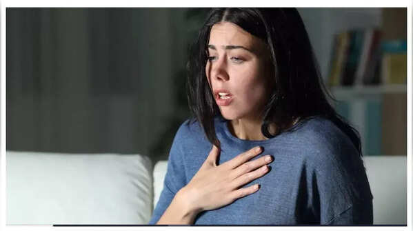 A person's hand over their heart, signifying heart palpitations